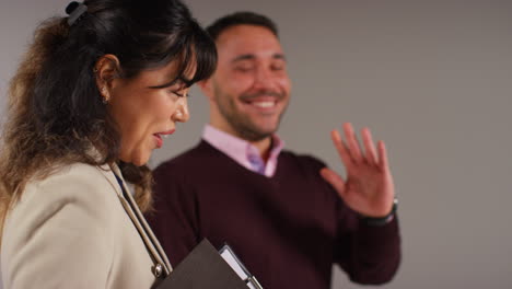 Nahaufnahme-Einer-Studioaufnahme-Von-Männlichen-Und-Weiblichen-Lehrern-Vor-Grauem-Hintergrund,-Die-Zusammen-Lachen-Und-Lächeln