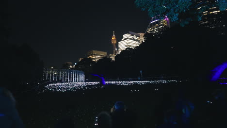 Hunderte-Von-Weißen-Blinkenden-Lichtern-Auf-Dem-Boden-Mit-Menschen,-Die-In-Zeitlupe-In-Den-Botanischen-Gärten-Von-Sydney-Zusehen