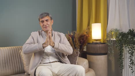 un anciano disculpándose mirando a la cámara.
