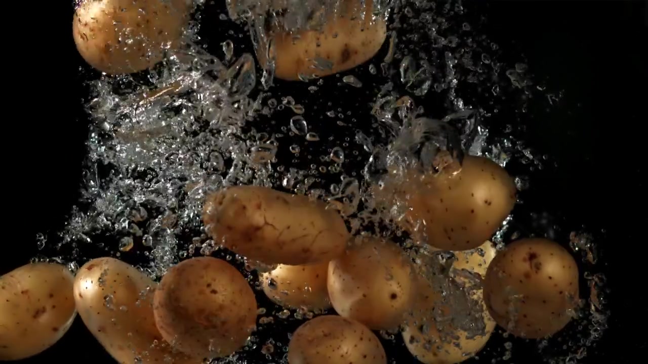 Patate fresche che cadono in acqua con schizzi e bolle