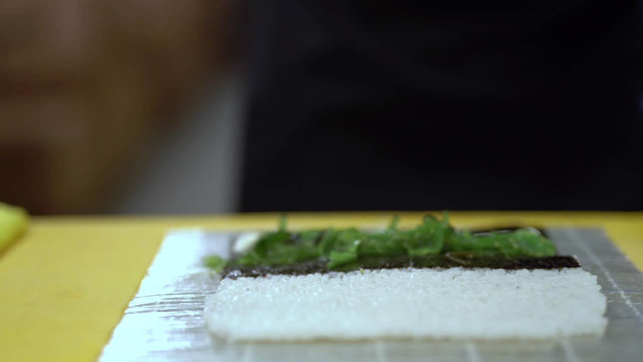 un cocinero está a punto de preparar un rollo de sushi con algas y mejillones