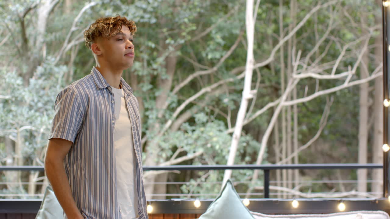 Young man enjoying peaceful moment outdoors on balcony surrounded by nature, copy space