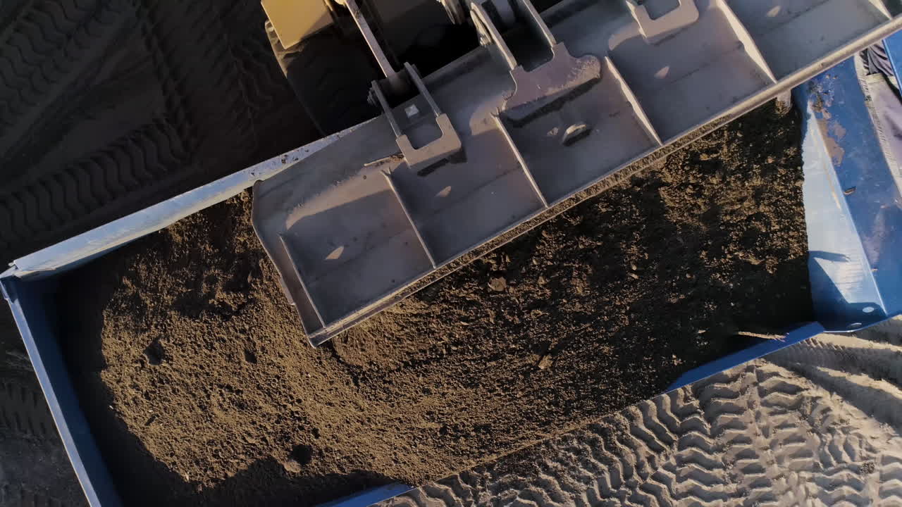 sitio de construcción con excavadoras y camiones que cargan materiales