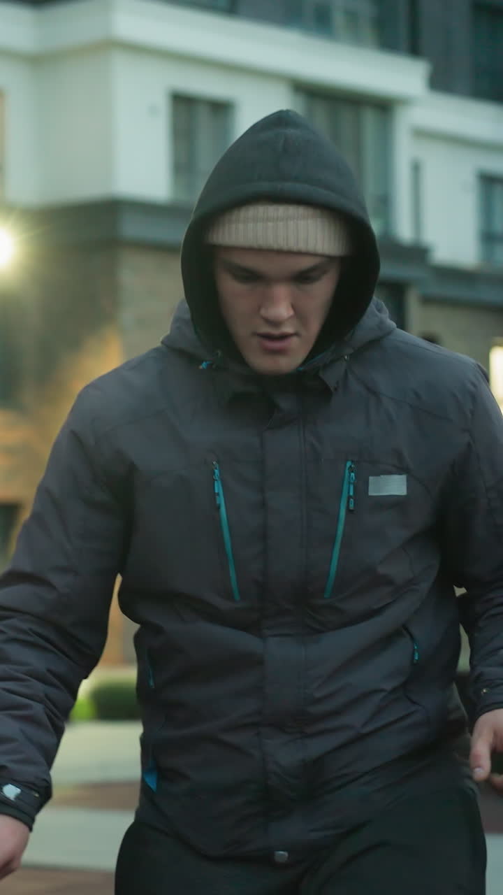 Athlete skillfully juggling soccer ball during training in urban sport arena, demonstrating focus and control against a backdrop of light up residential buildings, and outdoor fitness equipment