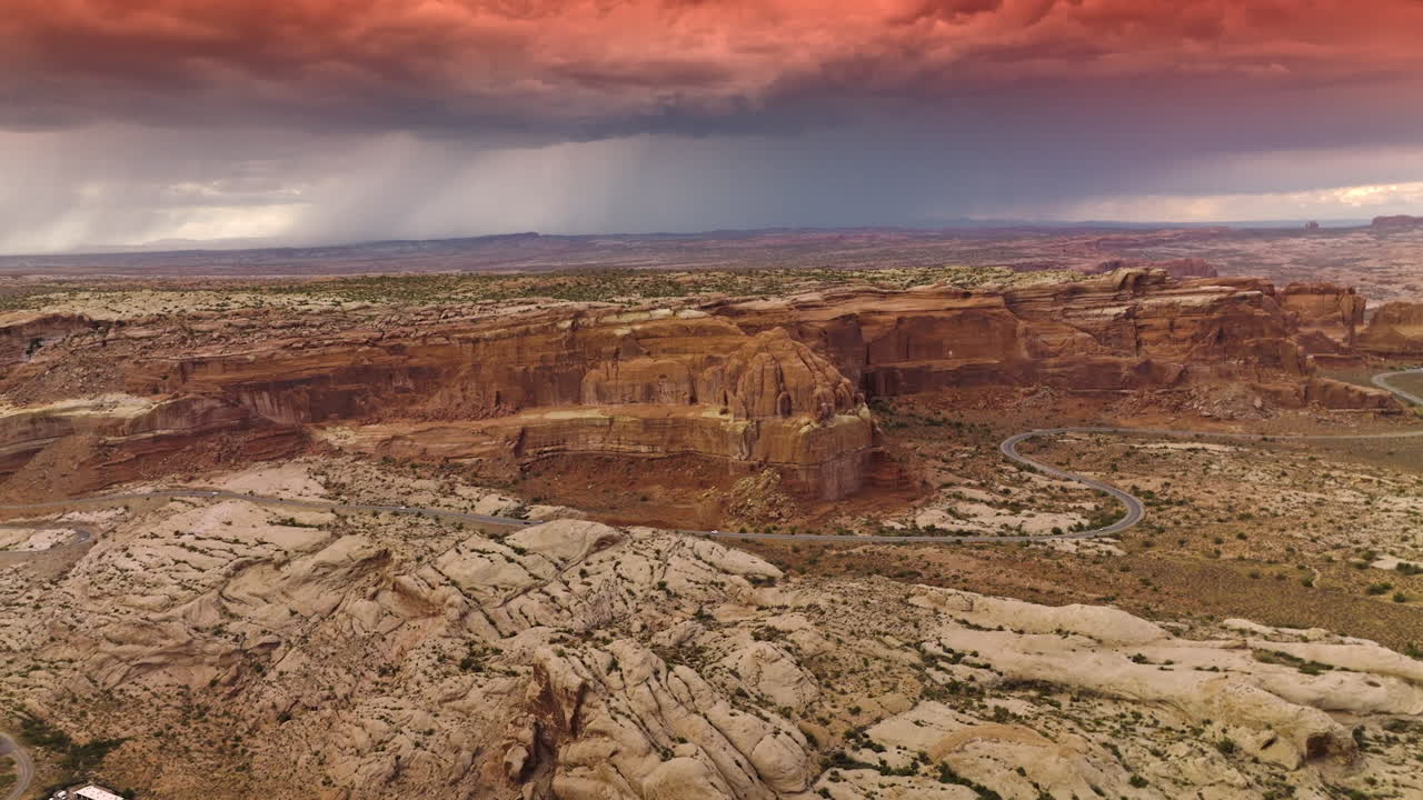 Amazing dramatic blue and pink cloudscape over the majestic canyon in Utah, USA. Wavy highway with cars moving on running near the rocks.