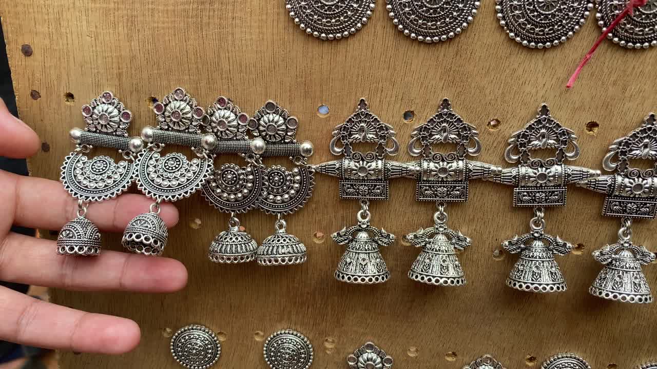 mano de una niña mirando aretes hechos a mano a la venta en el shantiniketan en bengala occidental, india