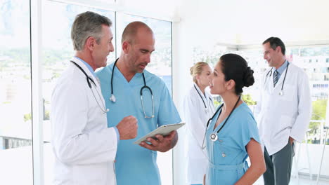 Medical-team-using-tablet-computer-with-their-colleagues-behind