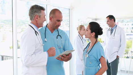 equipo médico usando computadora tablet con sus colegas detrás