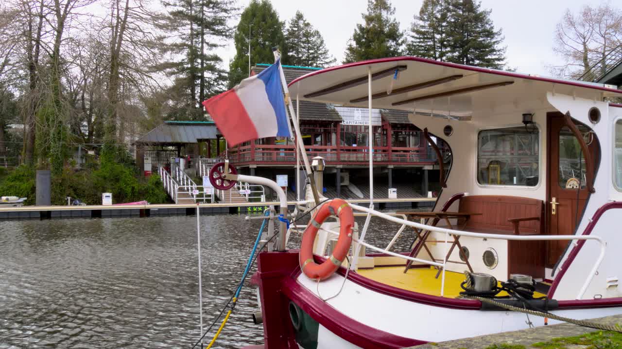 좁은 보트가 프랑스의 에르드르 강에 앉아 있고 뒤쪽에 프랑스 국기가 펄럭인다