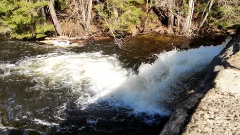 clip de mano de agua que fluye por la presa en cámara lenta en un día soleado