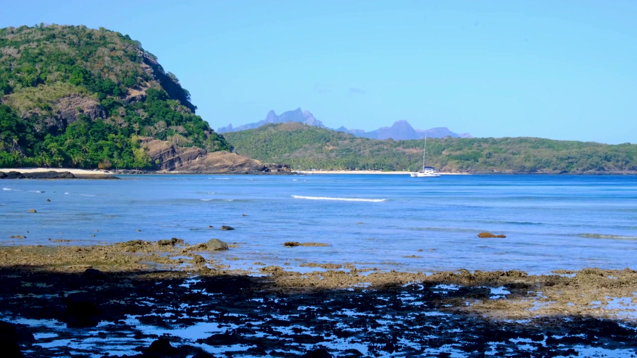 Vista panoramica di un paesaggio aspro e suggestivo di isole tropicali con yacht ancorato nell'oceano con bassa marea nelle Isole Yasawa, Fiji