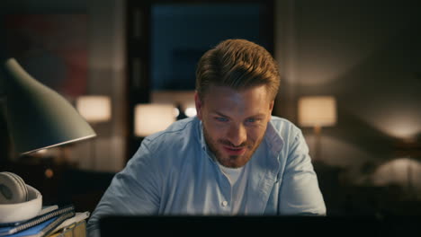 laughing guy chatting computer cozy apartments closeup. person reacting on joke