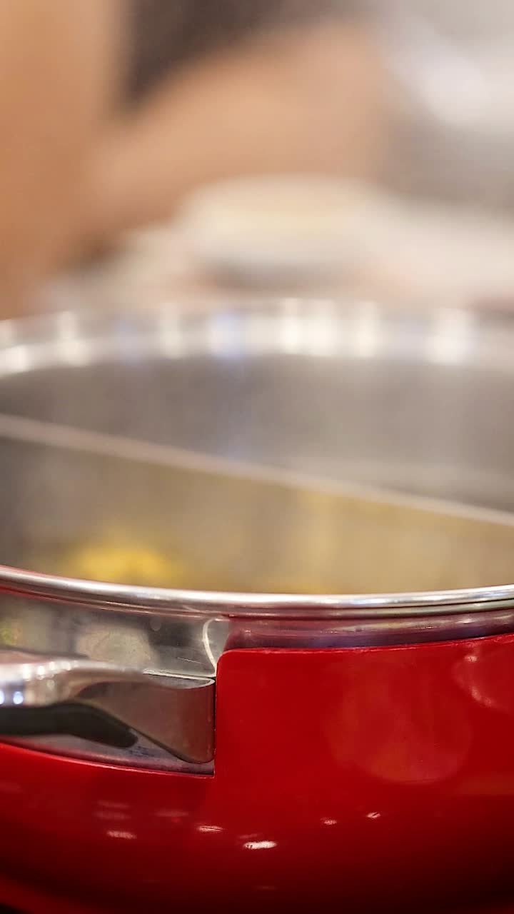 Hands preparing hotpot at a dining table
