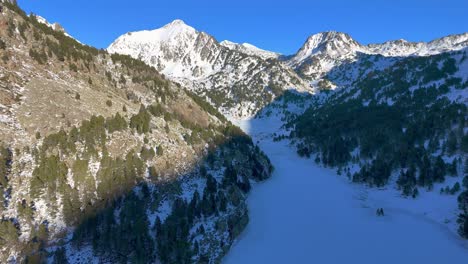 imágenes de drones de un valle helado con un lago congelado y árboles bajo la nieve en las montañas de los pirineos