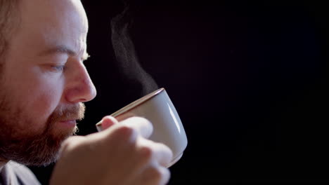 slow motion backlit - a man drinks from a steaming cup of hot beverage