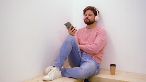 Man-browsing-and-listening-to-music-on-smartphone-in-coworking-space