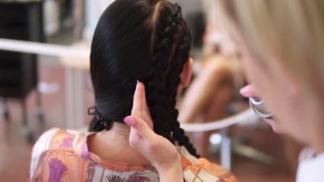 Close-up-female-hairdresser-hands-finishing-volumizing-hairstyle-use-fixing-hairspray-to-girl-customer.-Young-beautiful-woman-having-gorgeous-hairdo-at-beauty-salon.-Slow-motion