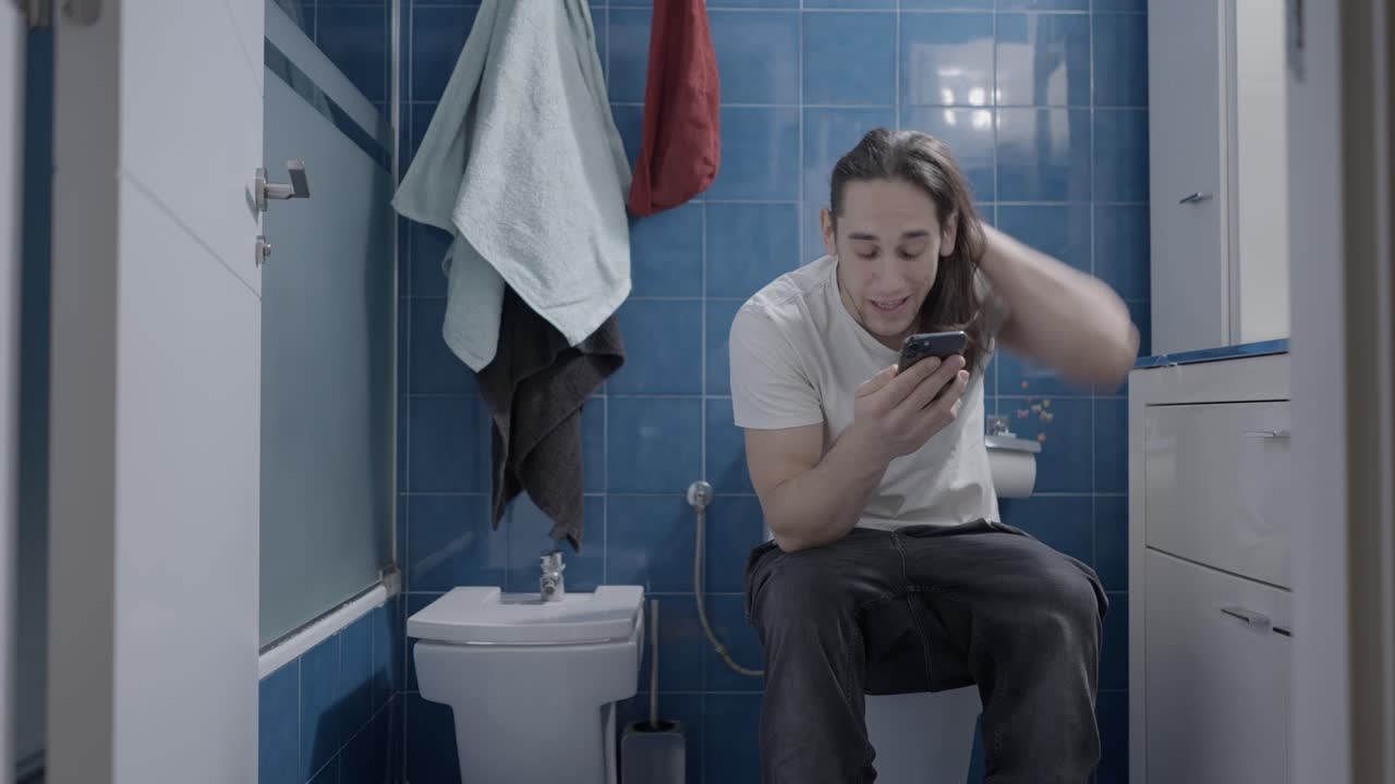 hombre usando un teléfono inteligente en un baño