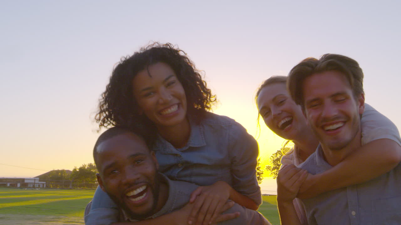 Two smiling couples piggybacking outdoors, close up