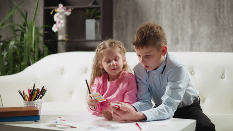 little girl pupil and brother learn subject with cards at home