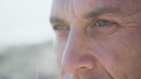 Close-up-of-Caucasian-man-enjoying-free-time-by-sea-on-sunny-day-looking-away