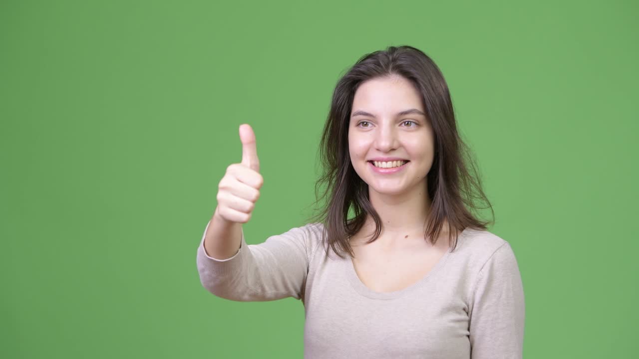 Young happy beautiful woman smiling while giving thumbs up
