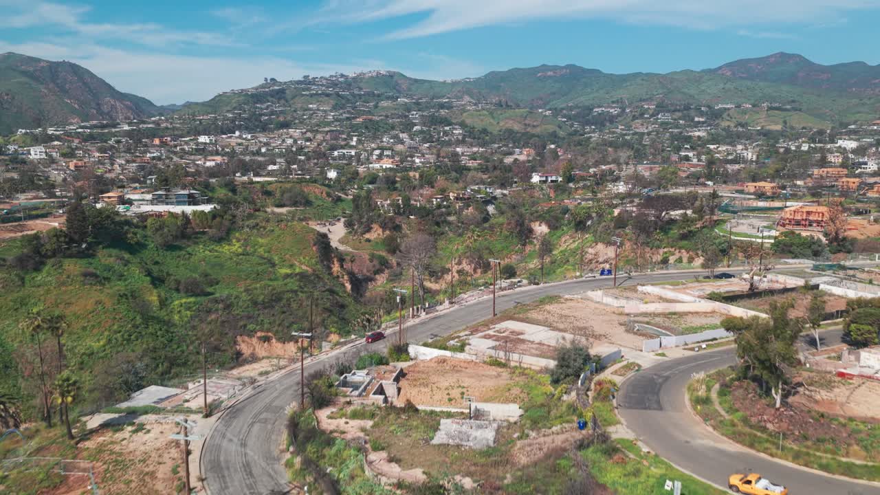 Ripresa aerea bassa in ascesa di Pacific Palisades durante il recupero dal disastro degli incendi boschivi in primavera a Los Angeles, California. 4K.