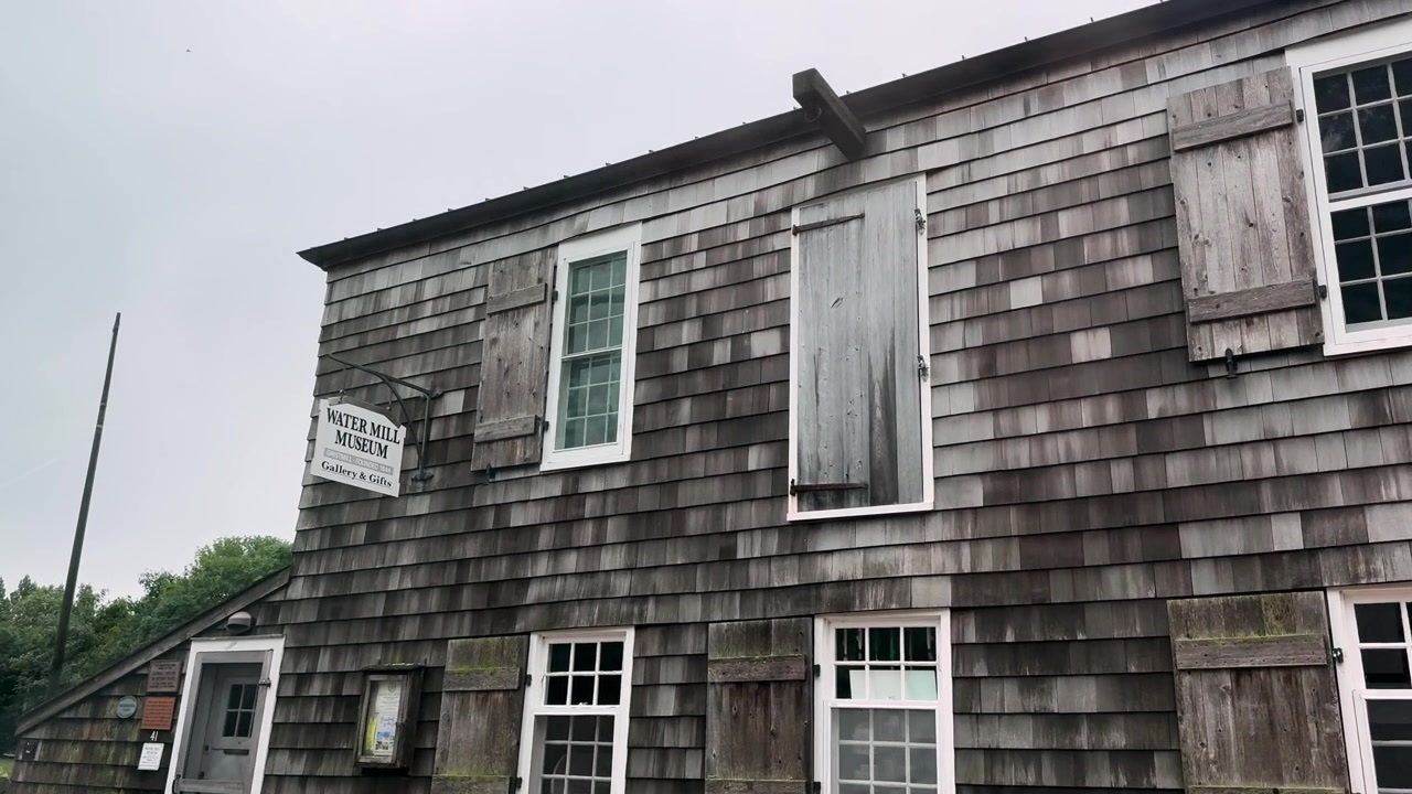 Historic wooden museum building with weathered shingles and shuttered windows