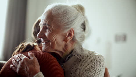 senior woman hugging granddaughter, smiling and talking to her