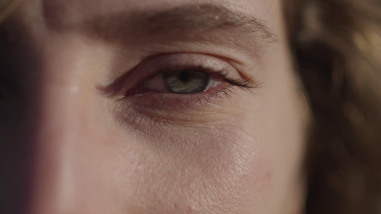 Close up of woman's eye slowly opening under strong natural sunlight