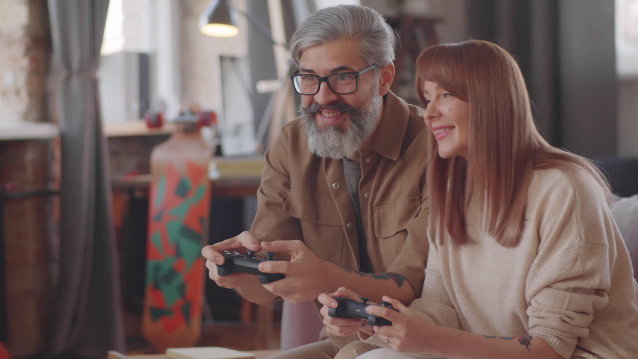 hermosa pareja de mediana edad disfrutando de juegos de consola y besándose