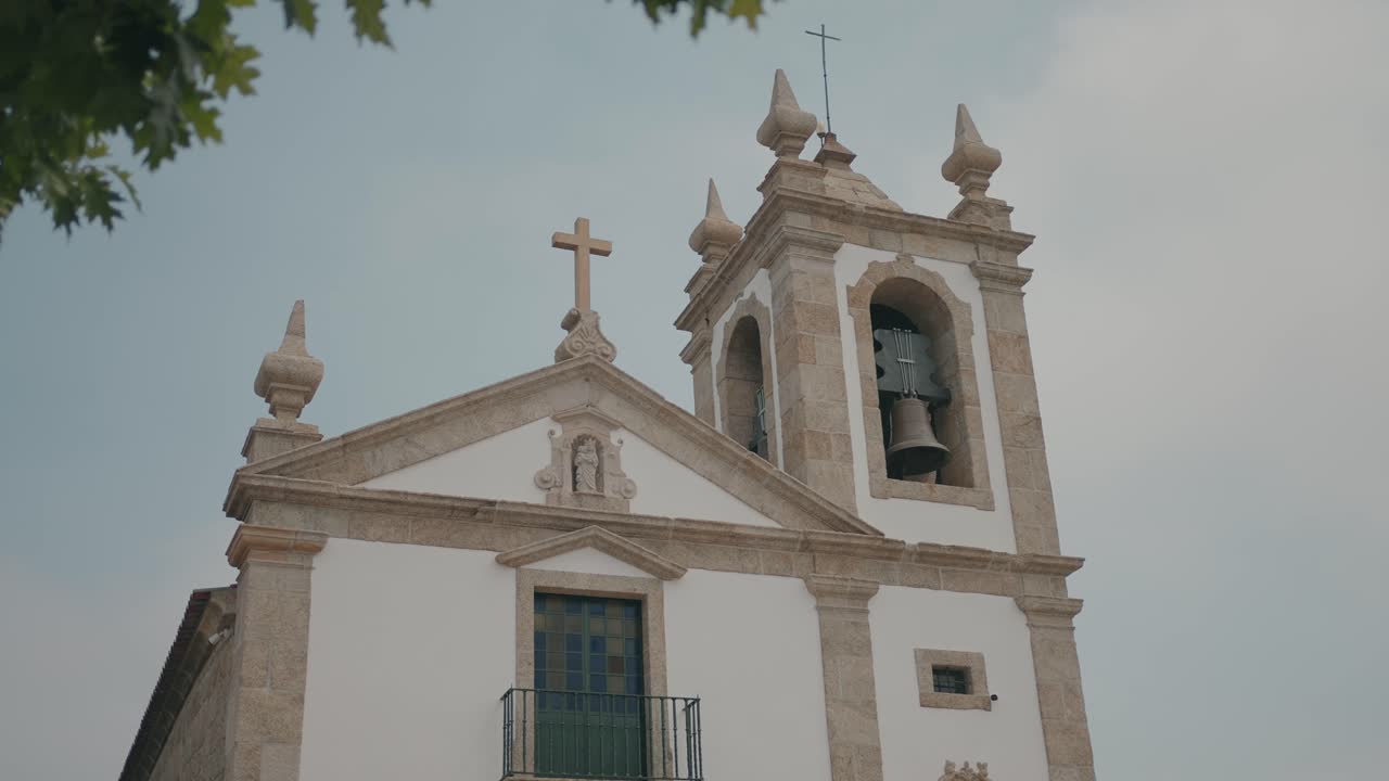 Vista esterna della facciata di una chiesa con croce sul campanile e dettagli in pietra