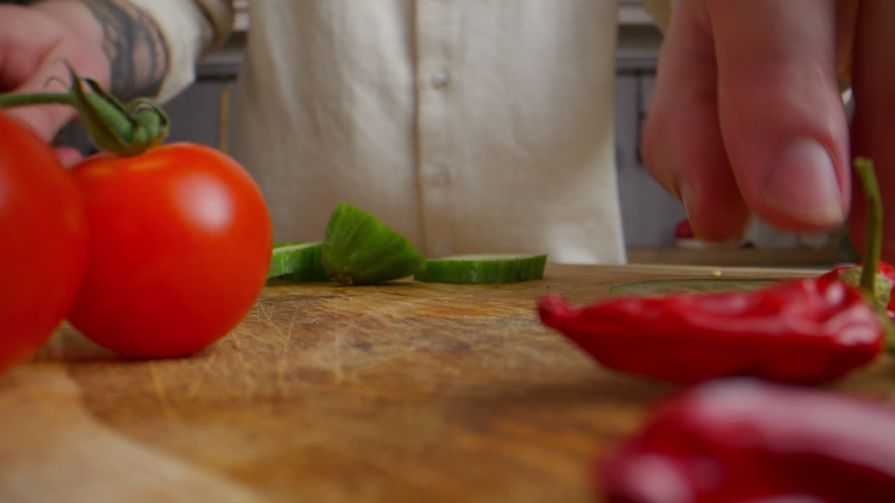 Preparing a salad with cucumber, tomatoes, and chili peppers