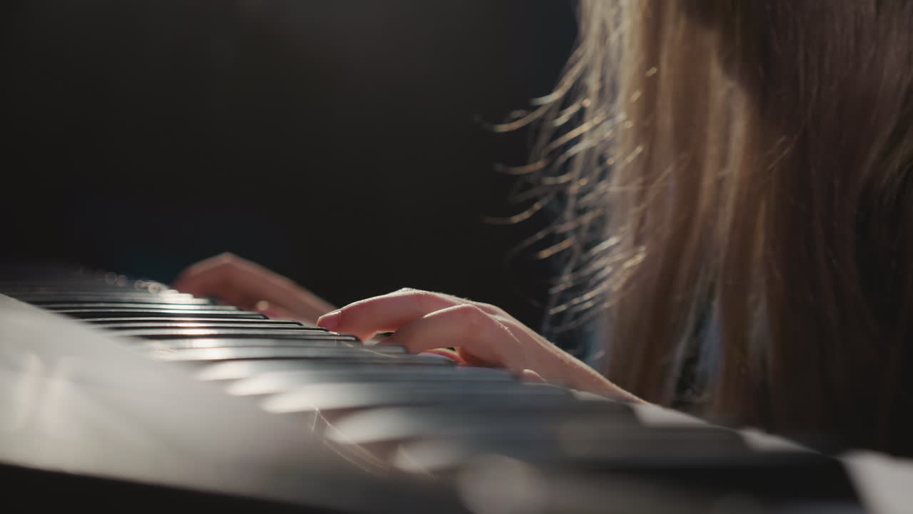 las teclas del piano sienten el toque de los dedos de la niña. la niña dotada se sumerge en las complejidades de la melodía durante la lección musical en el estudio de audio. talento musical de los niños
