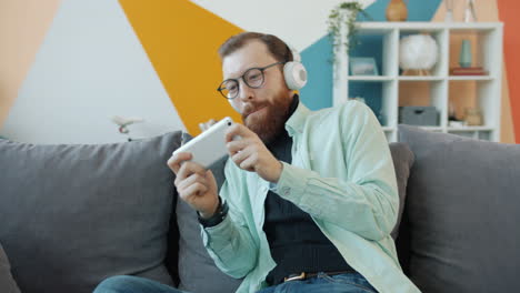 man playing mobile game on couch