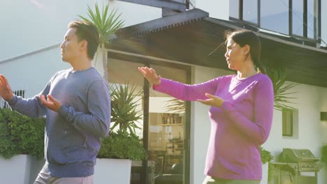 Video-of-relaxed-diverse-couple-exercising-tai-chi-in-garden