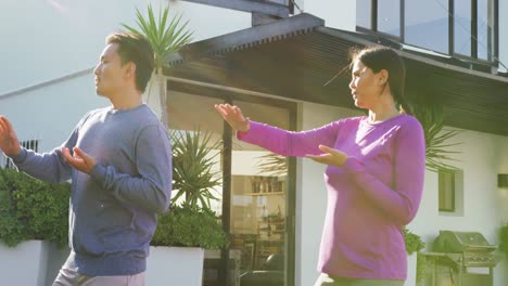 video de una pareja relajada y diversa ejercitando tai chi en el jardín