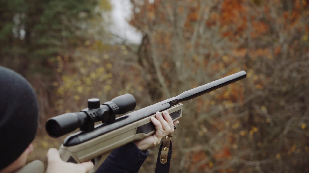 Hunter holding hunting rifle. Close up of young hunter holding hunting rifle aiming in forest