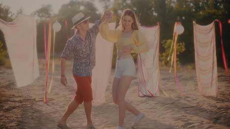 young couple dancing against sarongs hanging at beach