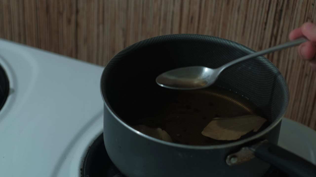 Close-up static shot of heating vinegar brine in a small saucepan.