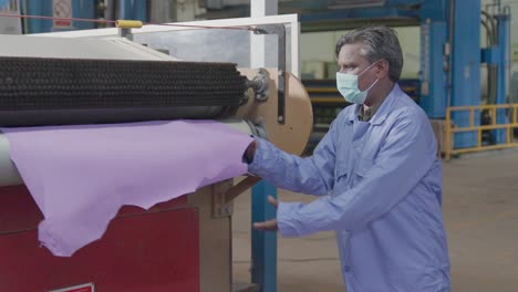 portrait of a machine operator processing tanned animal hides in a leather production factory.
