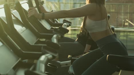 women train on a stationary bike in the gym. women do cardio exercises to increase endurance