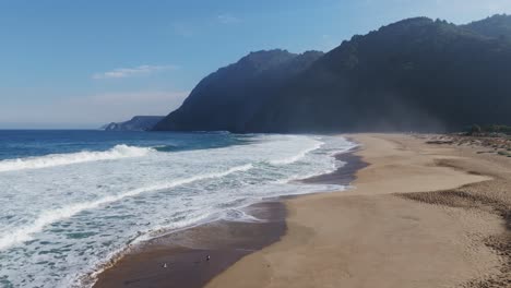 aerial low flying over playa grande beach coastline in quintay, chile showing waves crashing on the coastline