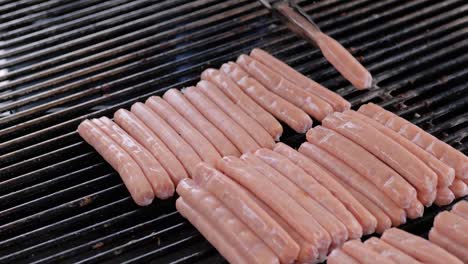 slow motion: chef grilling fresh meat sausages on big round hanging grill