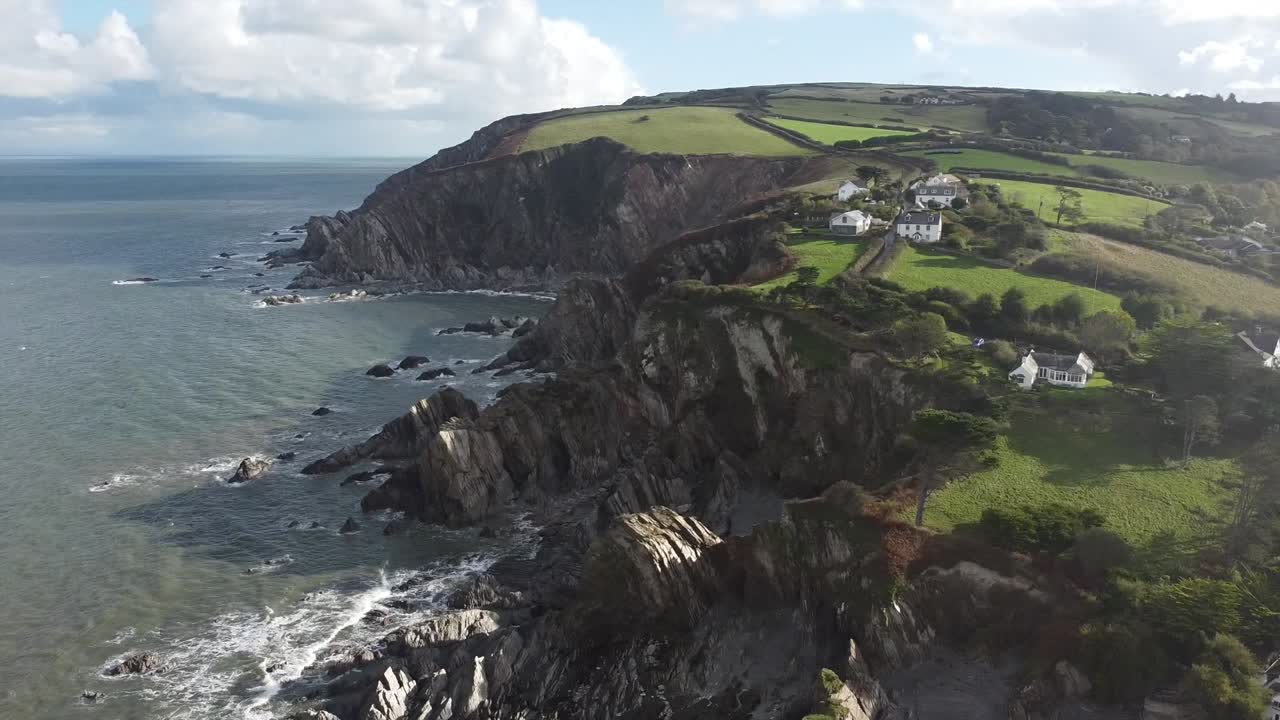 toma aérea de seguimiento de drones de casas sentadas en la cima de un acantilado rocoso - lee bay, beach, ilfracombe, devon, inglaterra