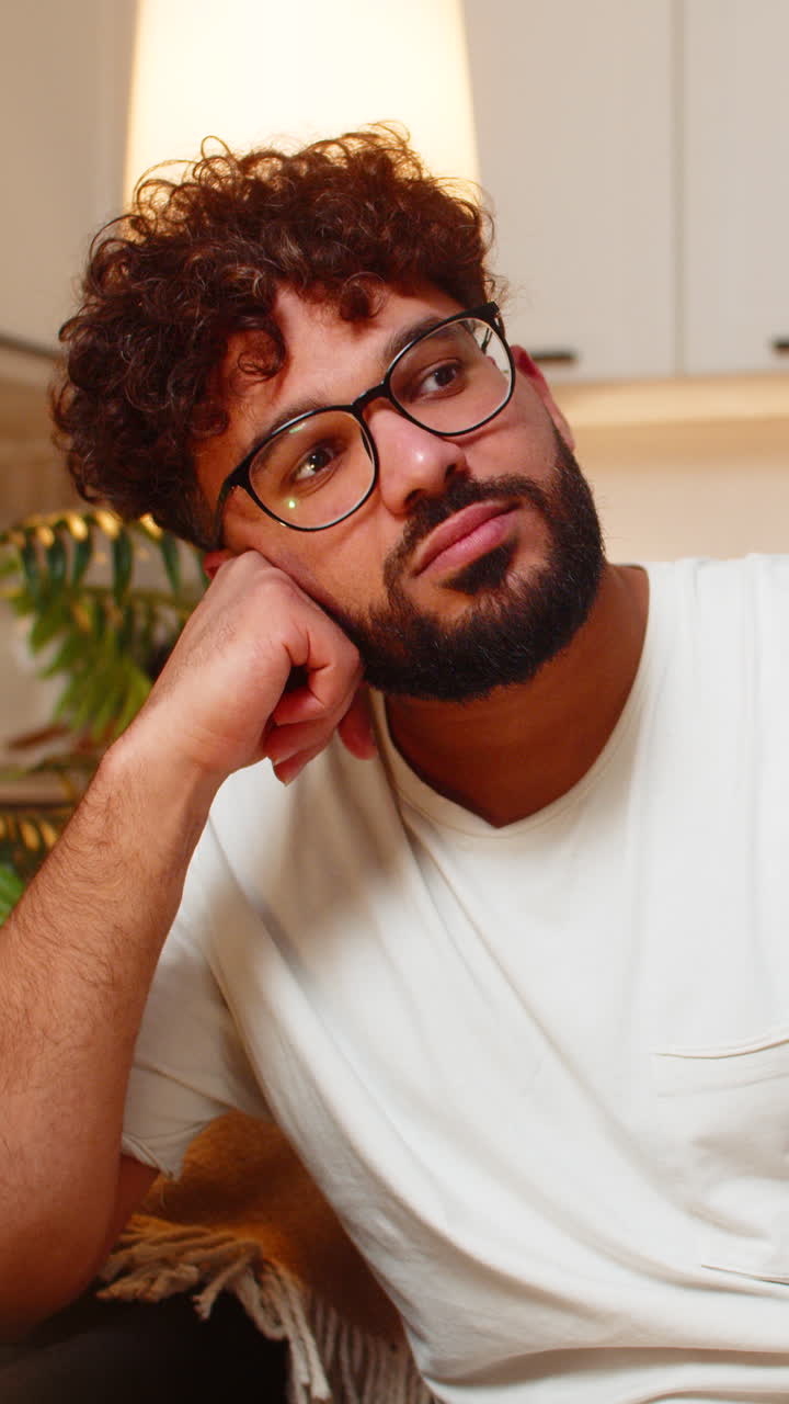 Arabian man sad at night after bad news indoors sitting on couch feels stressed very tired and upset