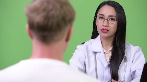 una joven médica asiática da consultas a un paciente joven.