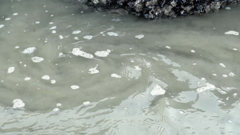 Swirling-ocean-water-on-sandy-beach-in-slow-motion