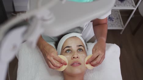 caucasian woman lying back while beautician gives her a facial