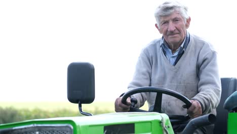 candid portrait of a senior farmer sitting in a tractor mature farmer working at agricultural machinery in farm